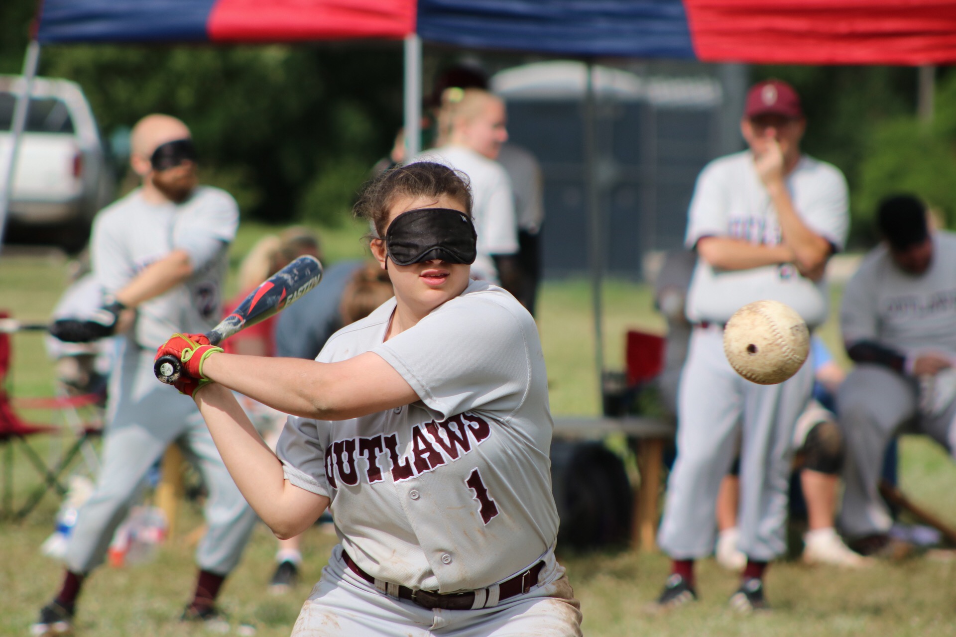 BCS Outlaw's Abigail Junek swings a bat towards the beep baseball hurtling towards her.