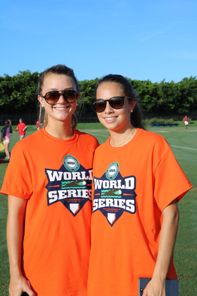 Two World Series volunteers smile for the camera from the sidelines.