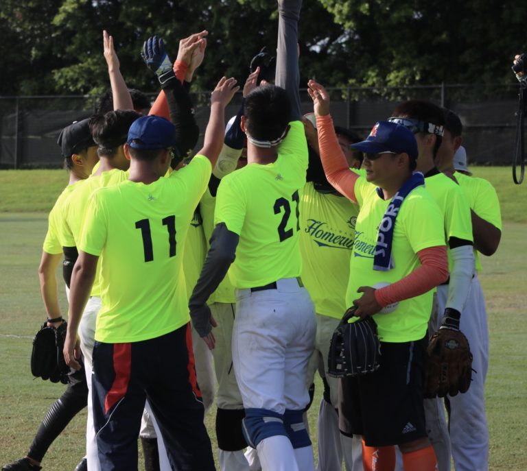 Taiwan Homerun huddle on the field with hands in the air.