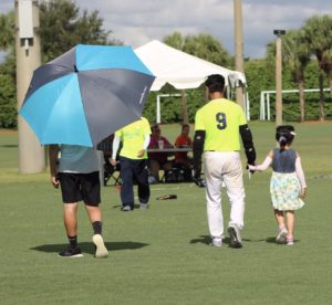 One of the littlest volunteers at the World Series holding a taiwanese player's hand as they walk back towards their teams' bench.