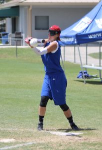 A female player from Canada is hitting the ball and the ball looks like it is wrapping around the bat.