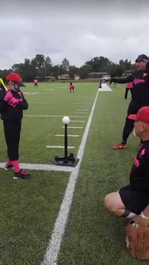 Tatyana Contreras readies herself in a batting stance as Tim Hibner and Brandon Chesser nearby to provide encouragement.
