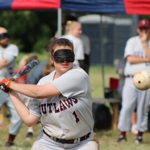 BCS Outlaw's Abigail Junek swings a bat towards the beep baseball hurtling towards her.
